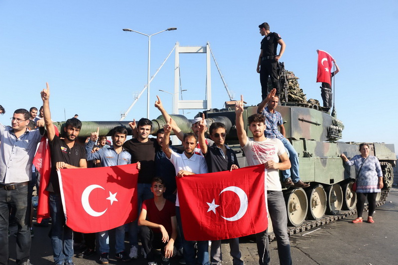 epa05427483 Turkish police and supporters of President Recep Tayyip Erdogan display the Turkish national flag as they cheer next to a tank on the Bosphorus Bridge after a failed coup attempt, in Istanbul, Turkey, 16 July 2016. Turkish Prime Minister Yildirim reportedly said that the Turkish military was involved in an attempted coup d'etat. The Turkish military meanwhile stated it had taken over control. According to news reports, Turkish President Recep Tayyip Erdogan has denounced the coup attempt as an 'act of treason' and insisted his government remains in charge. Some 104 coup plotters were killed, 90 people - 41 of them police and 47 are civilians - 'fell martrys', after an attempt to bring down the Turkish government, the acting army chief General Umit Dundar said in a televised appearance. EPA/STR
